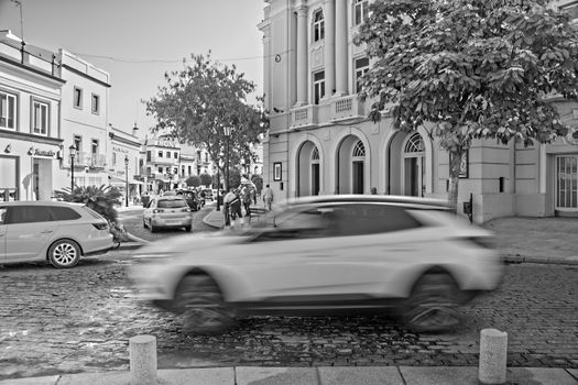 Black and white city street scene with blurred motion of cars in a vibrant urban setting.