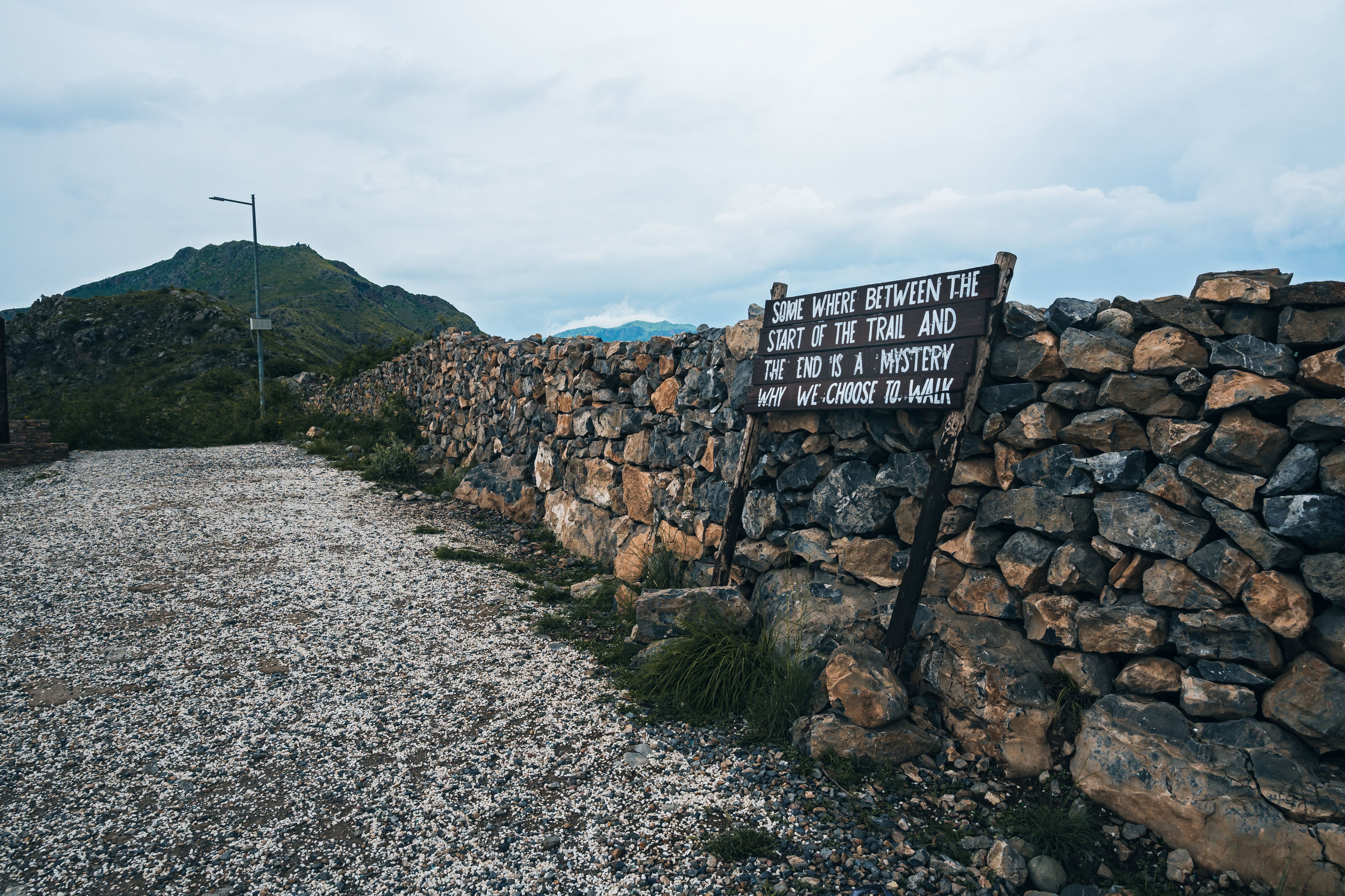Explore the scenic hiking trail with stone walls and cloudy skies in Kohat, Pakistan.