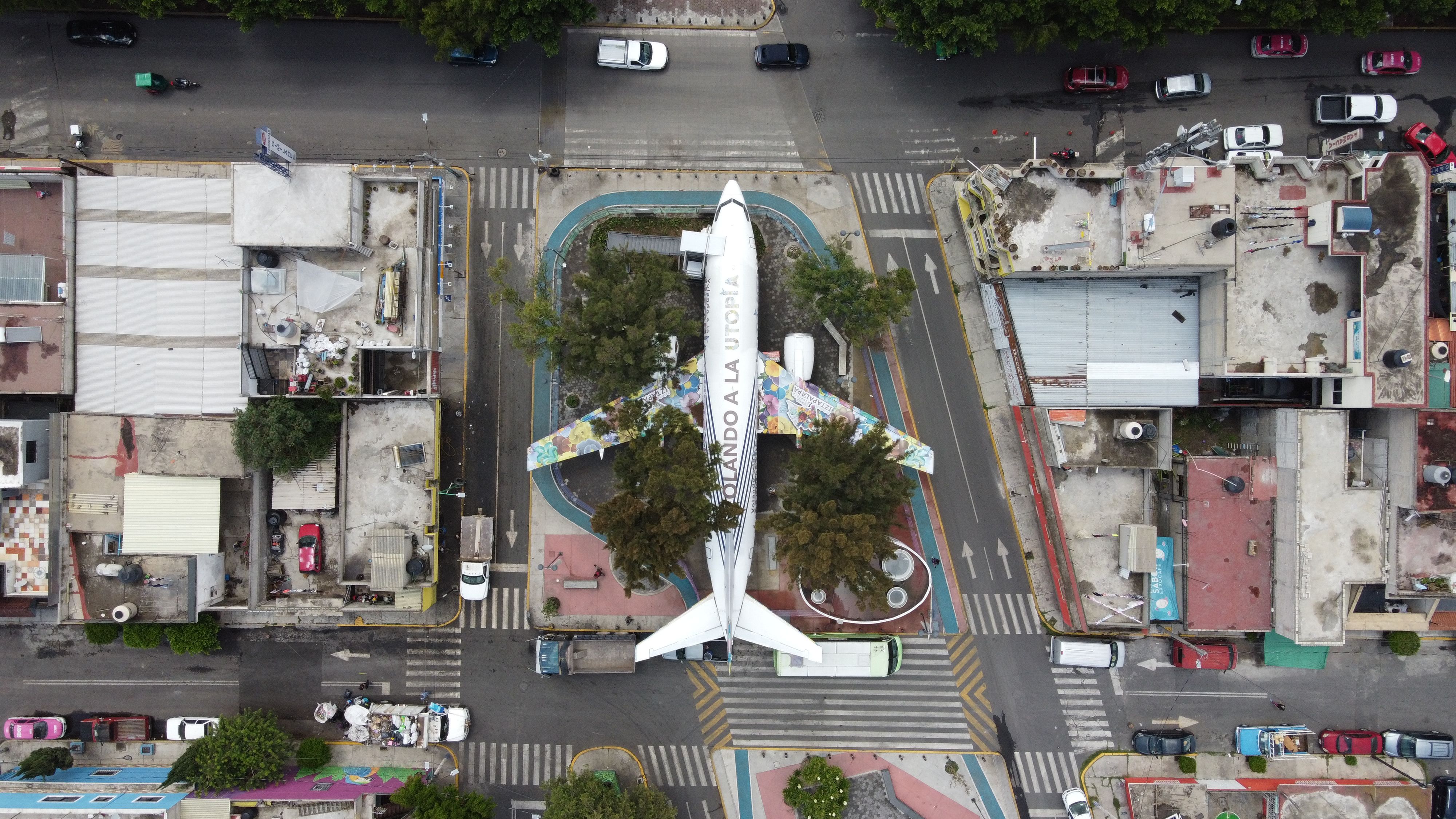 Aerial view of airplane structure in a park in Ciudad de México surrounded by urban buildings.