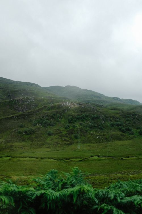 Free A scenic view of rolling green hills and a cloudy sky portraying natural beauty. Stock Photo