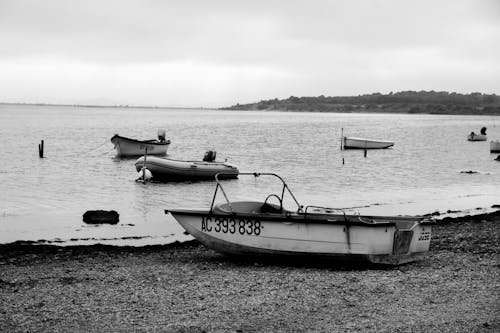 Grayscale Photo of Boats on the Sea Shore