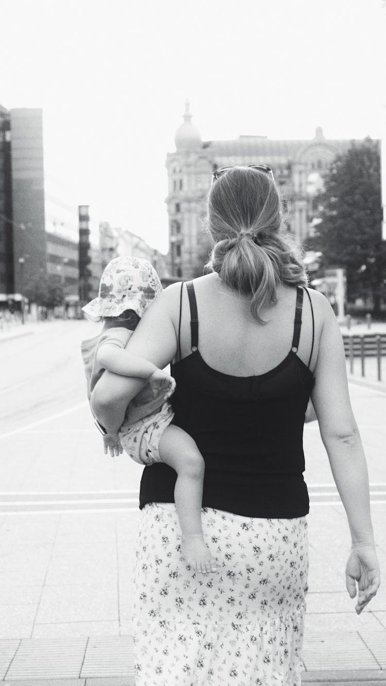 Grayscale Photo Of Woman Carrying A Child