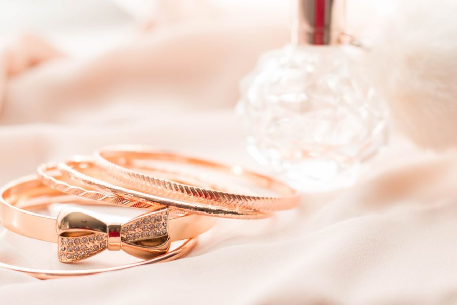 Gold bangles and a crystal perfume bottle on pink silk