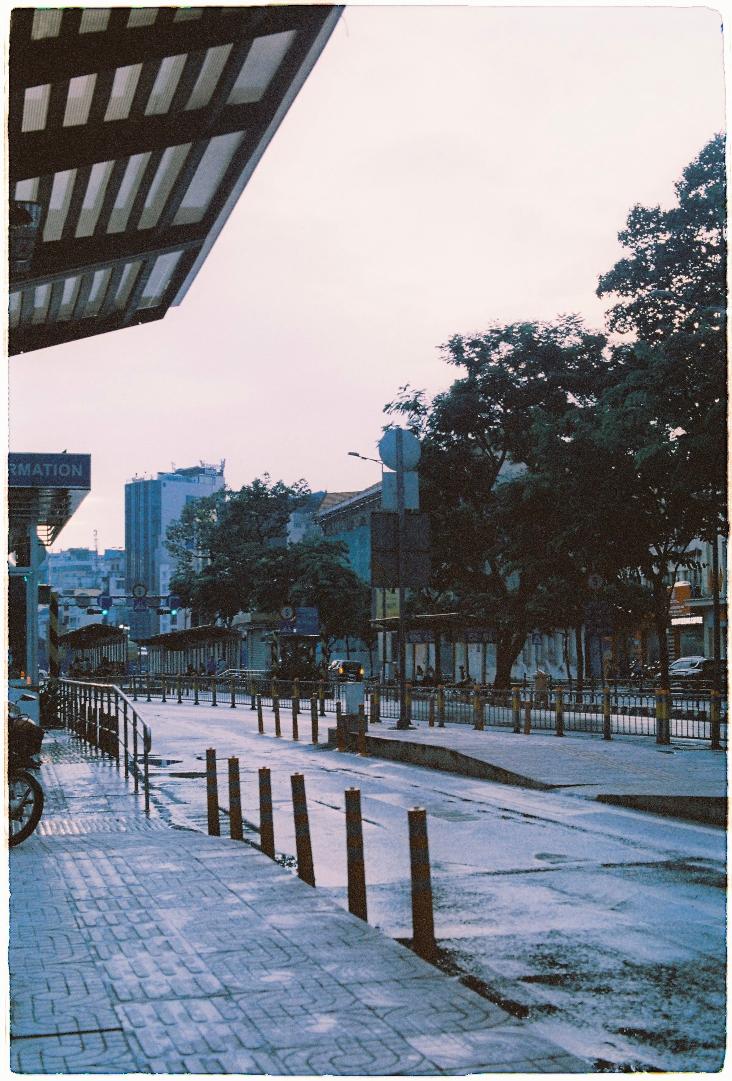 A serene city street view at dusk, showcasing urban architecture and trees.