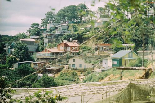 Free Charming hillside village with vibrant houses amidst lush greenery. Stock Photo