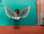 在多伦多市中心，一位女人在充满活力的壁画前摆出天使翅膀的姿势