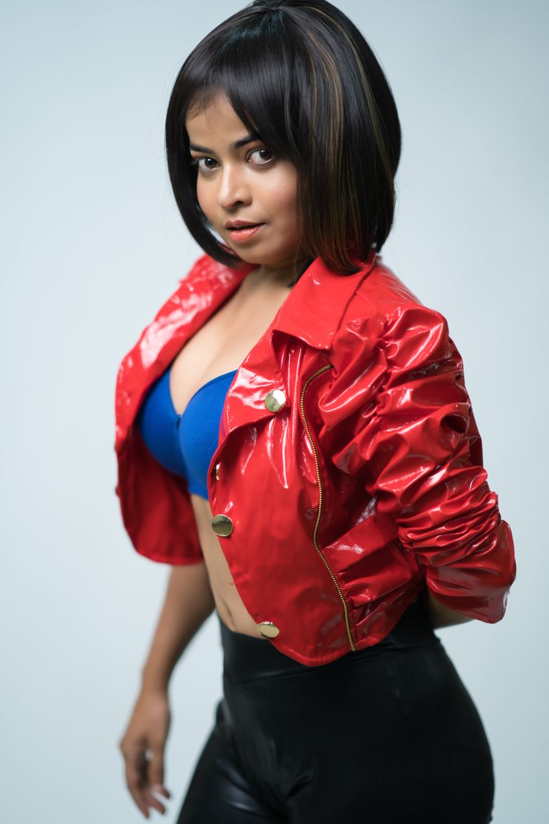 Portrait of a stylish woman in a red leather jacket with a white background.