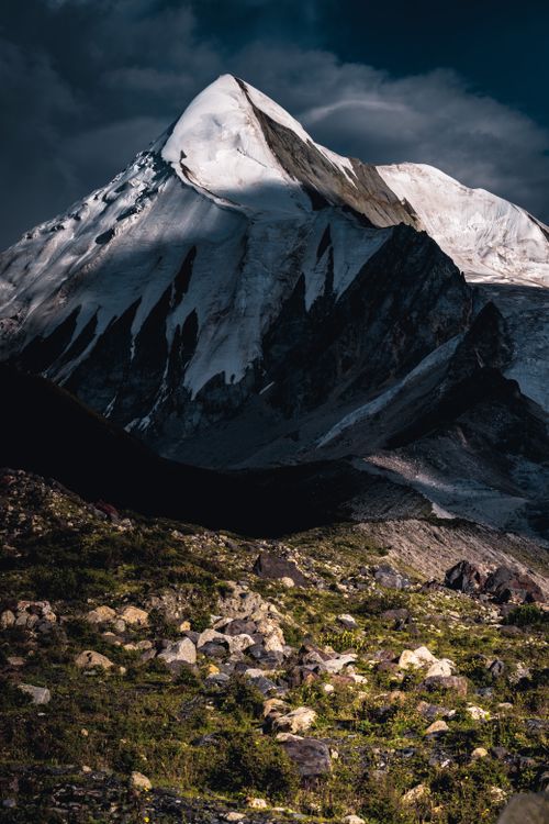 Free Stunning snow-covered mountain peak with rocky terrain beneath, captured during a dramatic sunset. Stock Photo