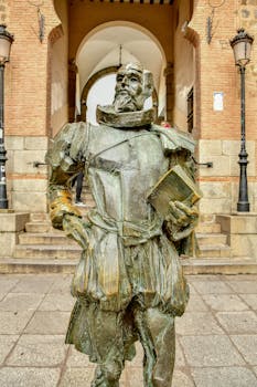 Statue of a historical figure holding a book in a European architectural setting.