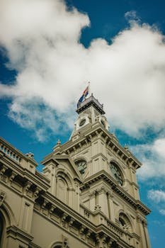 Elegant clock tower with intricate Victorian architecture set against a vibrant blue sky.