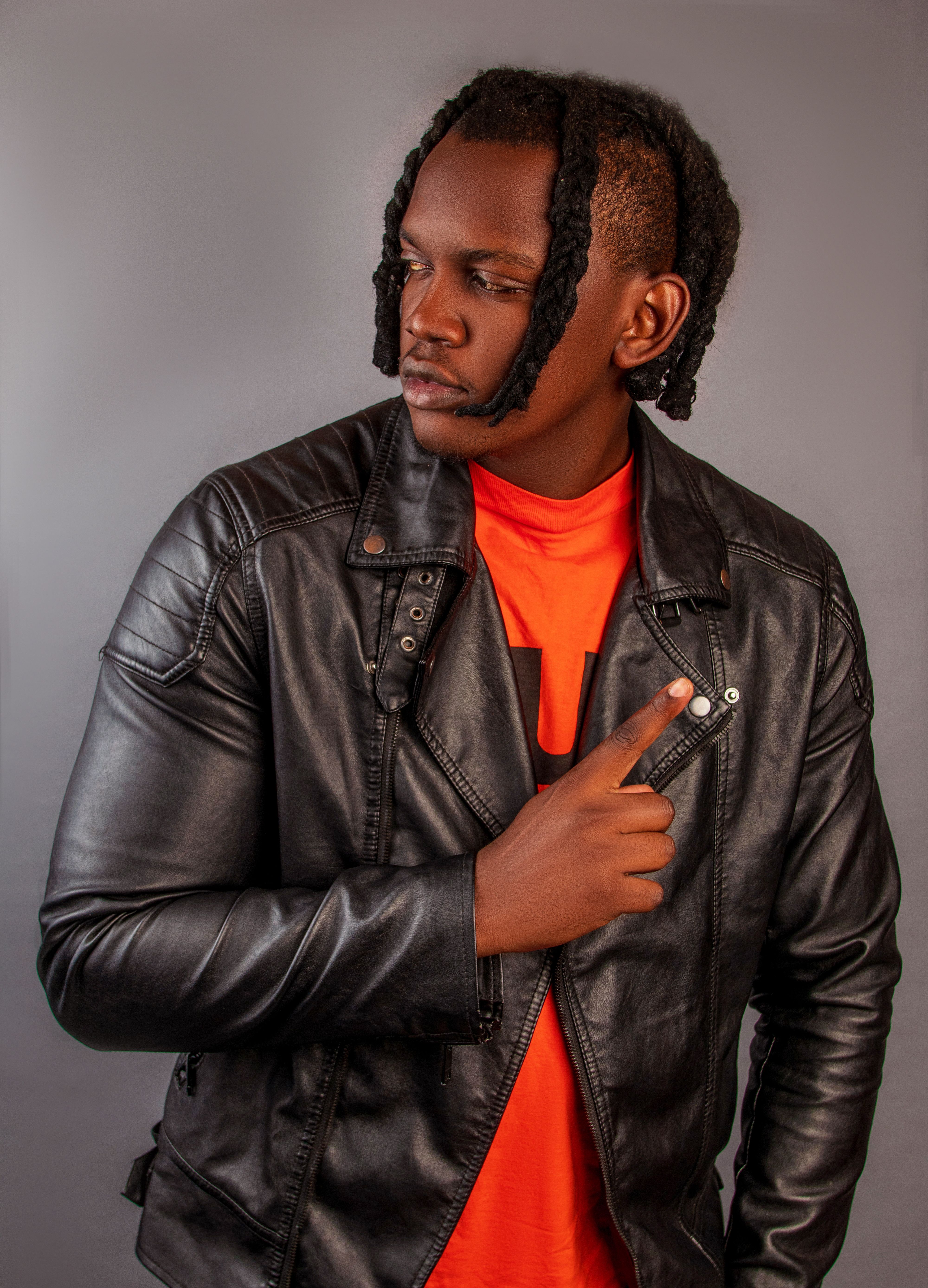 Portrait of a stylish man wearing a black leather jacket in a studio setting with a light grey background.