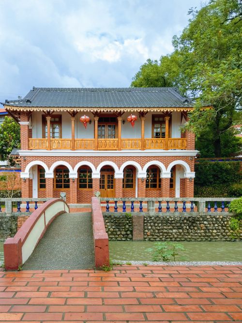 Free Scenic view of a traditional Asian building by the riverside with a bridge in the foreground. Stock Photo