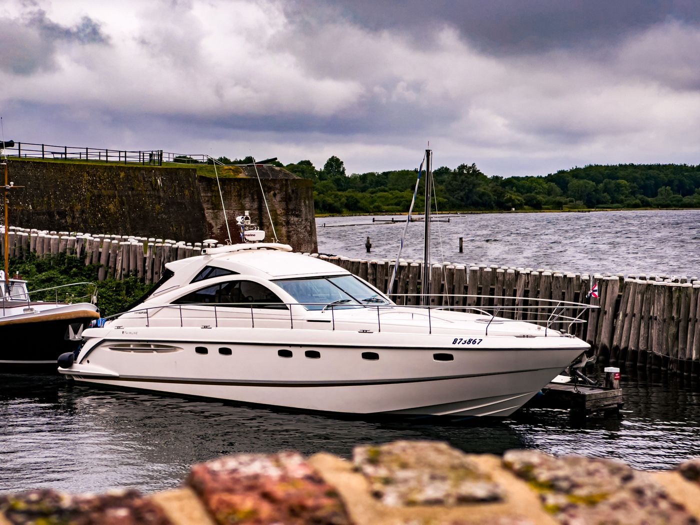 White 50-metre yacht moored alongside a stone harbour wall
