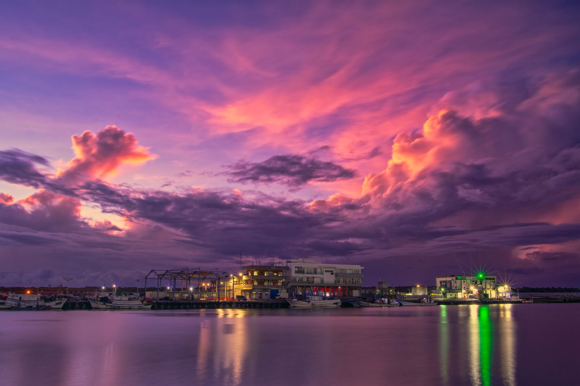 Dramatic twilight sky over a harbor in Taiwan, featuring vibrant clouds and calm waters.