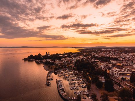 A stunning aerial view of Friedrichshafen, Germany during a dramatic golden hour sunset by the waterfront.