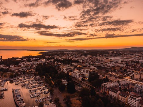 Stunning aerial shot of Friedrichshafen, Germany at sunset with vibrant orange sky.