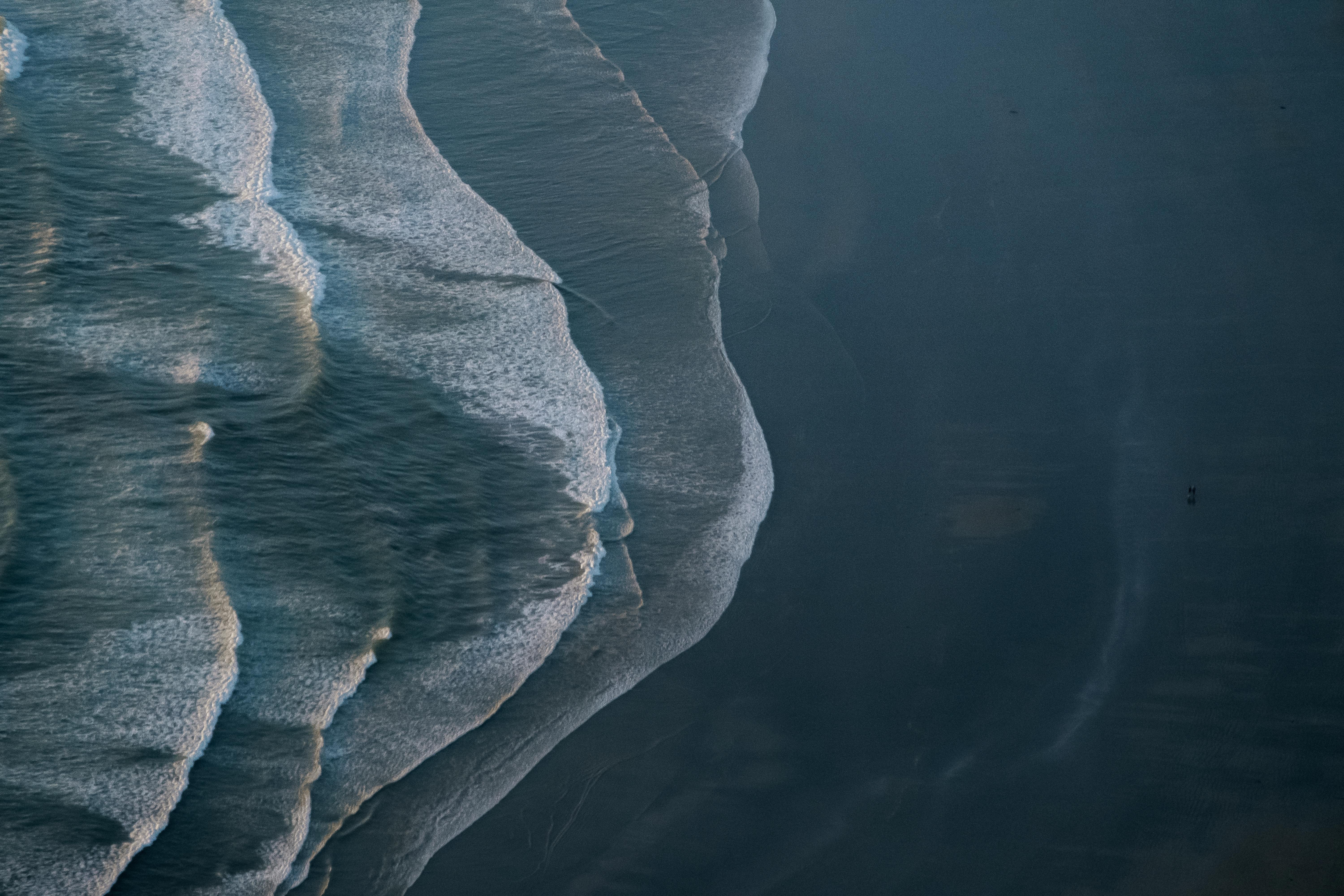 Aerial photo of ocean waves crashing on the shore at Tofino, BC, Canada, showcasing the beauty of black sand beaches.