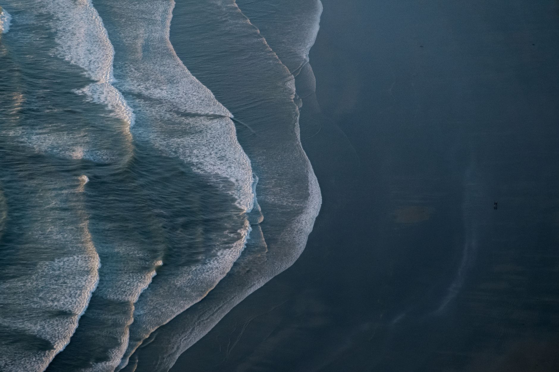 Aerial photo of ocean waves crashing on the shore at Tofino, BC, Canada, showcasing the beauty of black sand beaches.