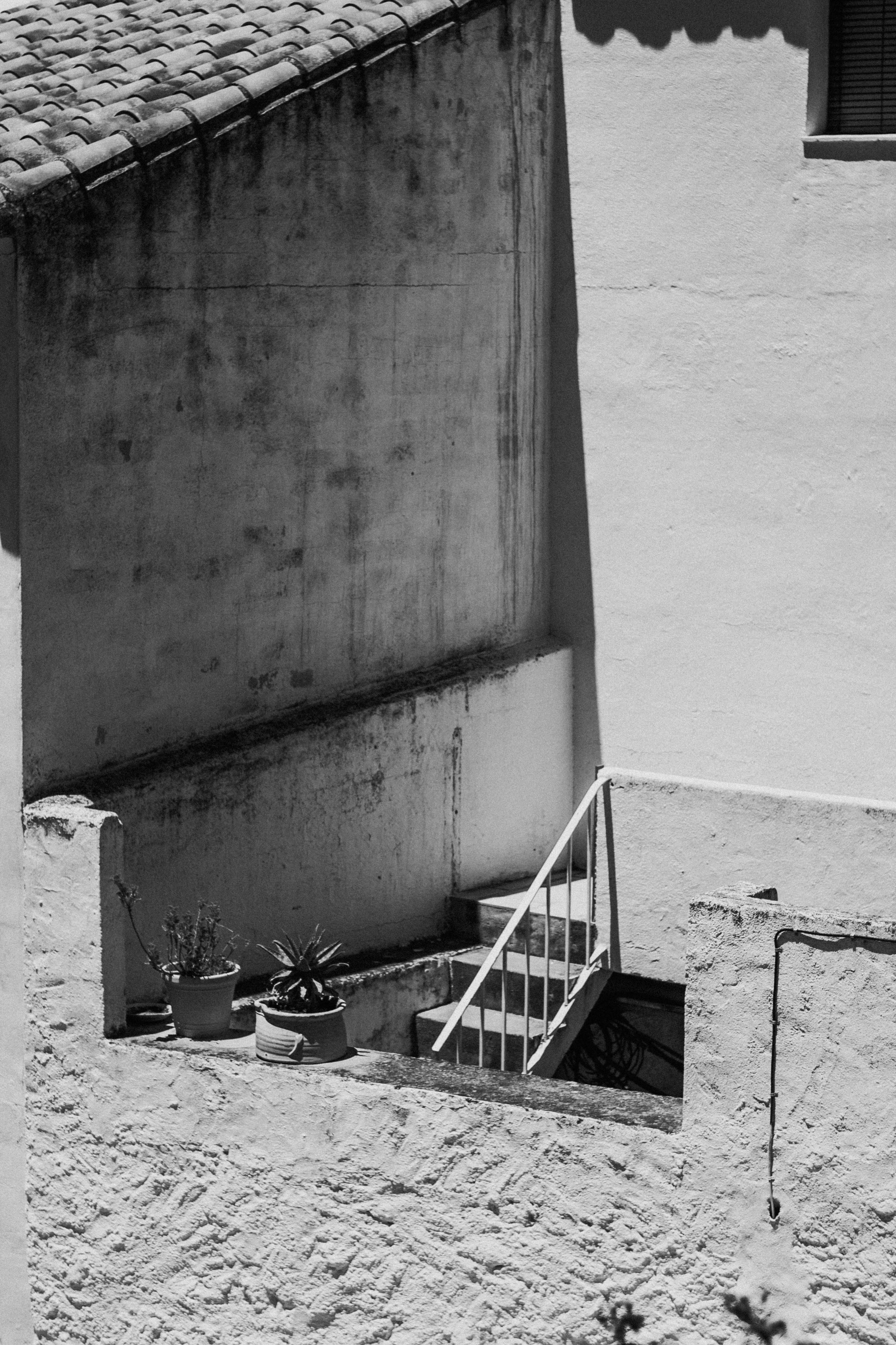 Black and white photo of rustic Spanish architecture in Mijas, showcasing shadow play on building facades.