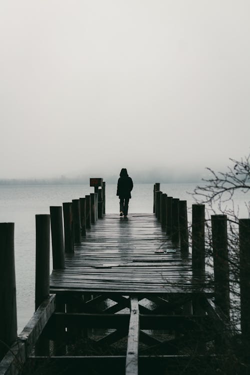 Person Walking on Pier near Water
