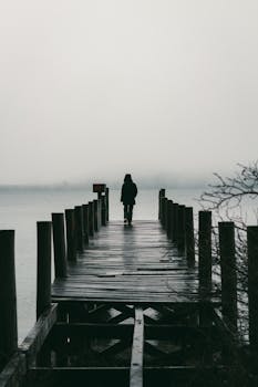Silhouette of a person walking on a foggy pier in Bariloche, Argentina, capturing serene solitude.