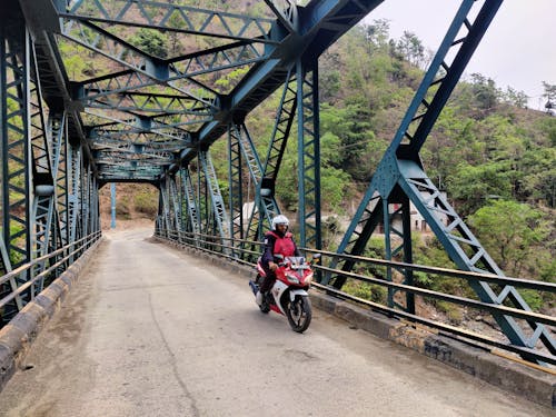 Man Riding on Red Motorcycle on Bridge