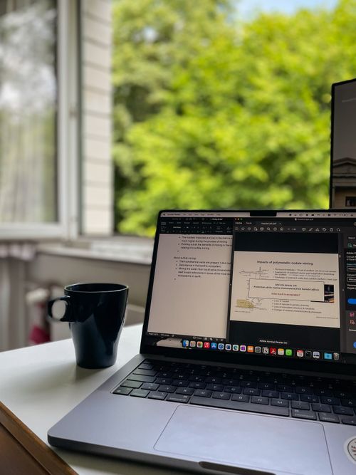 Free Laptop on desk with open window view and coffee cup, creating a relaxed workspace environment. Stock Photo