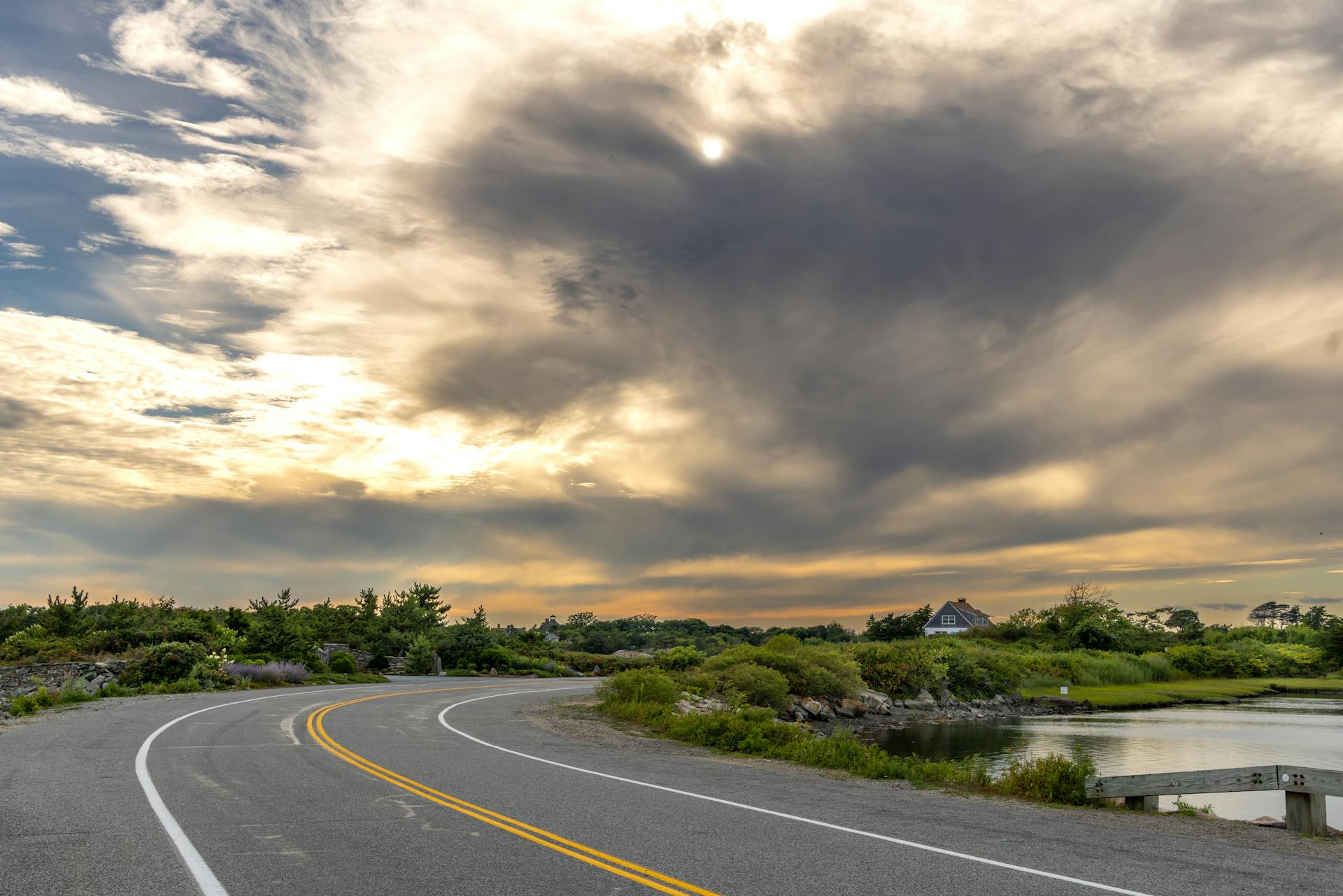 A peaceful road in New Shoreham, Rhode Island, with dramatic cloudy skies during sunset.