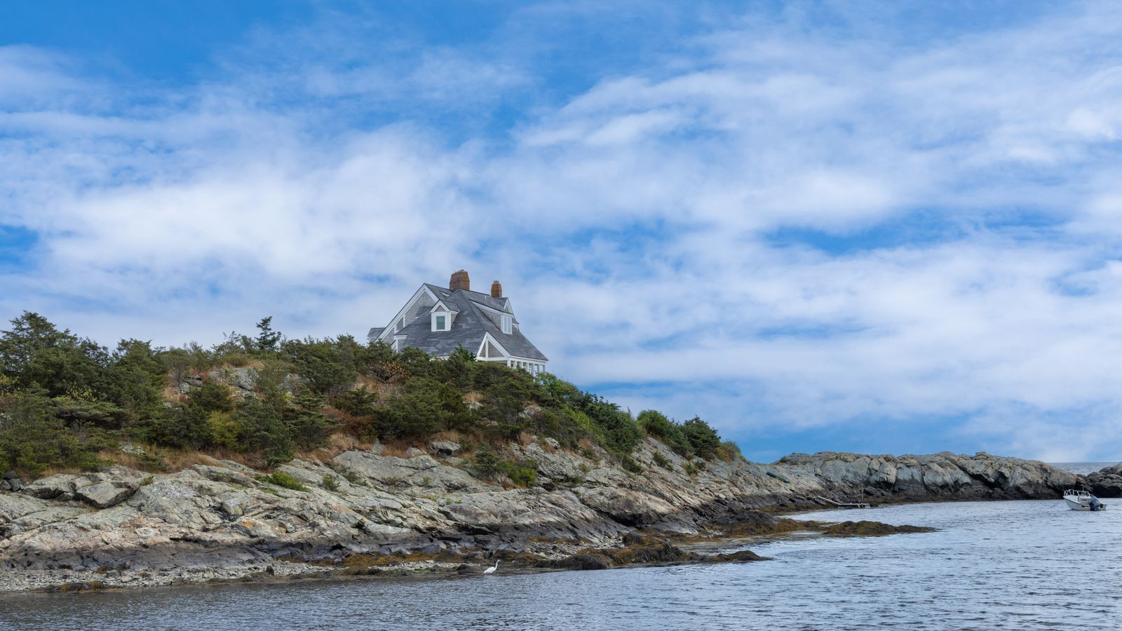 A beautiful coastal house perched on a rocky shoreline in New Shoreham, Rhode Island.