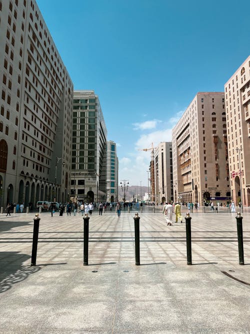 People Walking on City Street between Concrete Buildings