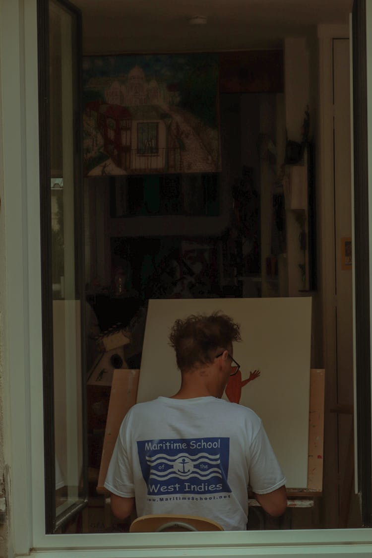 Back View Of A Man Painting On Canvas