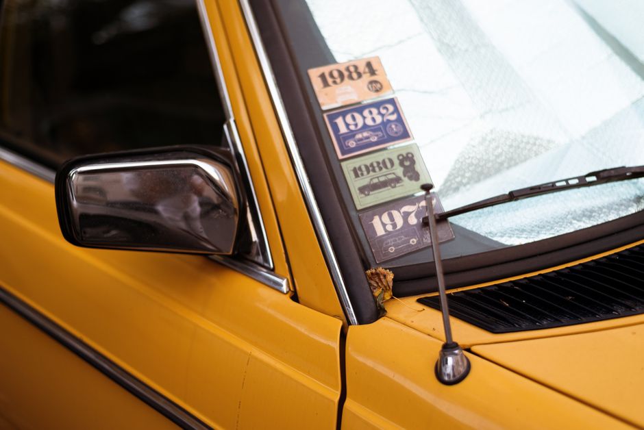 자동차세 연납 신청|할인받는 법 총정리 13 Close-up of a classic yellow car with retro decade stickers on the windshield.