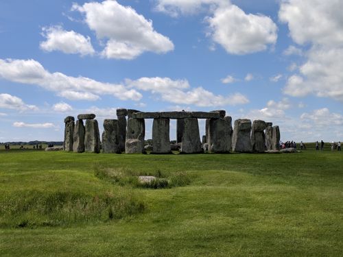 Free Majestic view of Stonehenge with a vibrant green field and cloudy blue sky. Stock Photo
