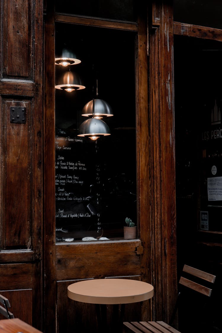 Lamps Behind Window And Table In Pub