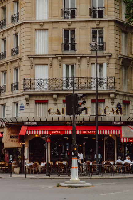 A bustling Parisian street corner with a classic cafe and urban atmosphere.
