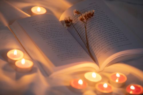 Free Open book surrounded by candles and dried flowers creating a warm, inviting atmosphere. Stock Photo