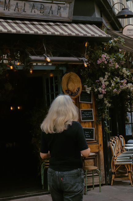 A woman strolls by a quaint Paris café, capturing the city's classic charm and inviting atmosphere.