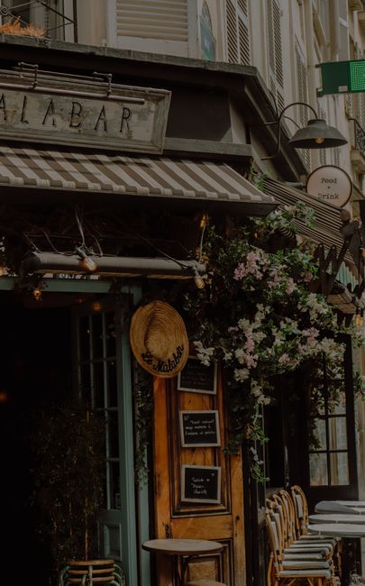 A cozy Parisian café exterior adorned with flowers and quaint signage, perfect for a French ambiance.