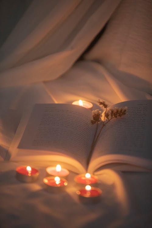 Candles Opened Book on White Textile