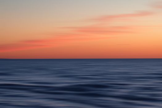 A tranquil sunset over the calm Baltic Sea, capturing the vibrant colors of the sky in Jūrmala, Latvia.