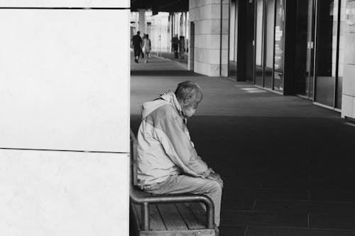 Fotografia In Scala Di Grigi Dell'uomo Seduto Su Una Sedia