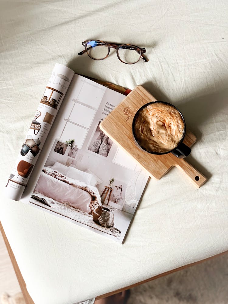 Close Up Of Coffee Cup, Magazine And Eyeglasses On Table