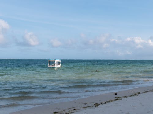 A Boat on an Ocean Near a Shore Under Blue Sky