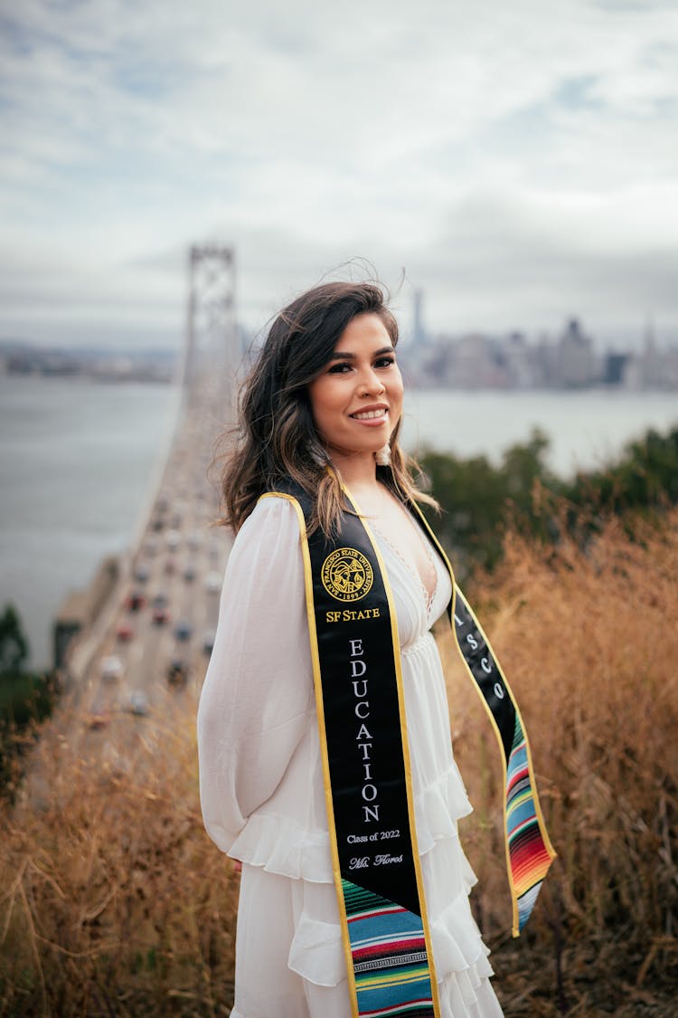 Woman Standing On A Hill Overlooking A Golden Gate Bridge In San Francisco And Wearing A Graduation Sash