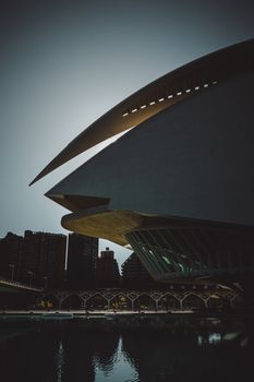 Dramatic view of modern architecture in Valencia, Spain, illuminated at dusk, reflecting in tranquil water.