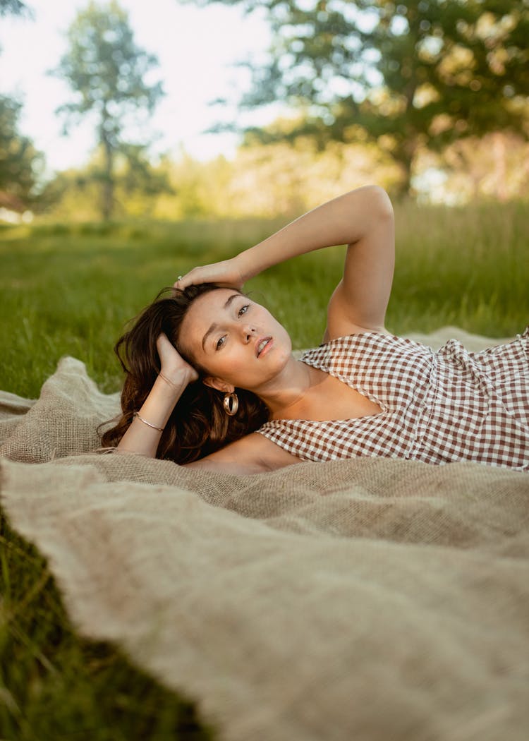 Woman Posing While Lying On A Picnic Blanket Outdoors In Summer 
