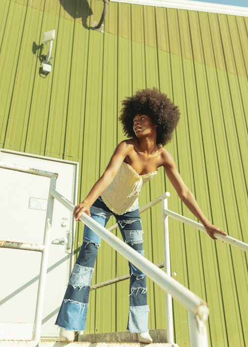 Woman Posing on Stairs in Front of a Building with Green Walls 