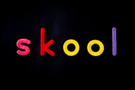 Colorful felt letters spelling 'skool' on a black background, close-up.
