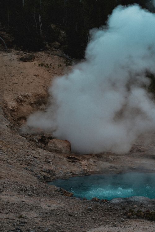 Free A geothermal hot spring releasing steam into the air, surrounded by rough terrain indicating volcanic activity. Stock Photo