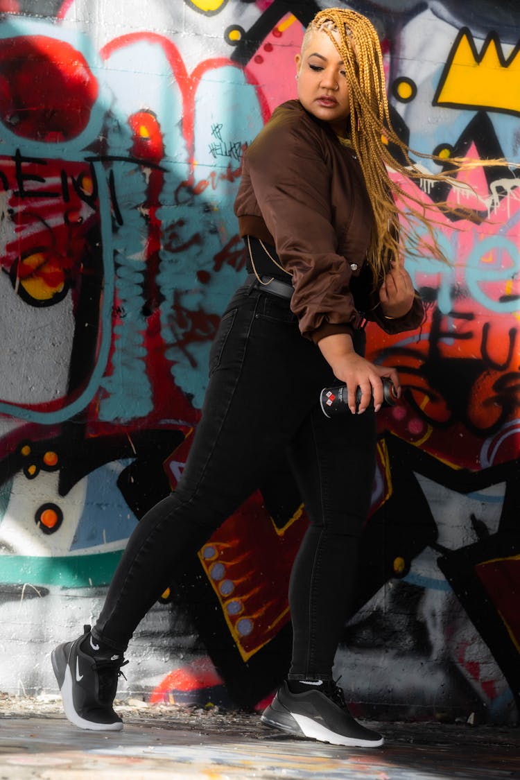 Woman In Brown Jacket Standing Beside Graffiti Wall